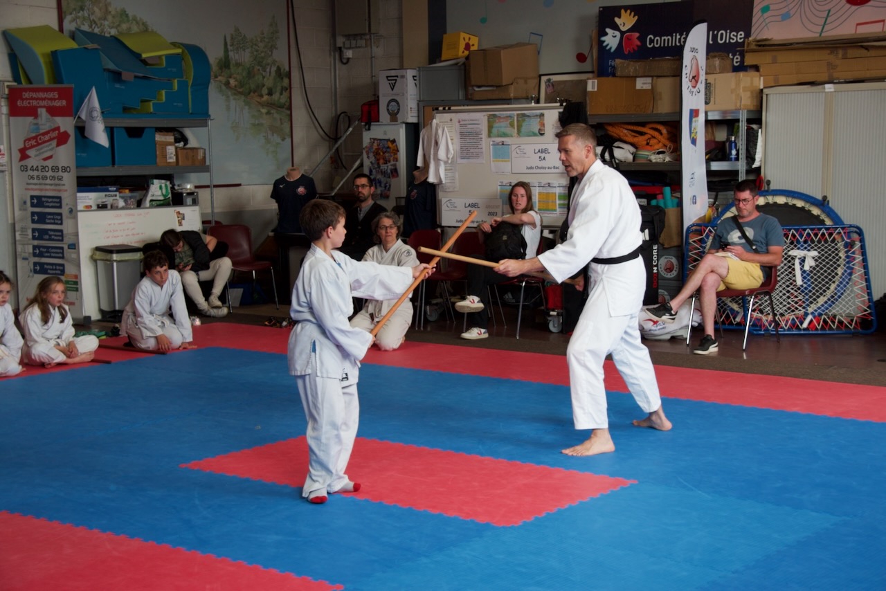 Un enfant et son professeur pratique face à face les mouvements au baton, simulant un combat